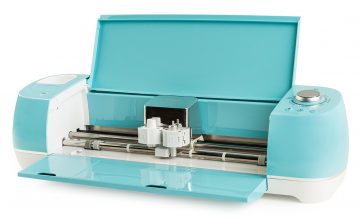 A light blue Cricut Explore is open, showing the inner workings and beginning to answer the question of "what is a Cricut machine?" - at least a little bit