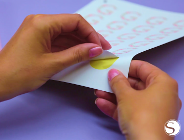 A woman peels a sticker off the page
