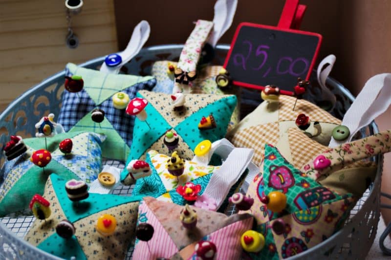 A bowl of colorful pincushions for sale at a crafts fair