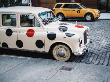 An old-timey car covered in red and black vinyl polka dots
