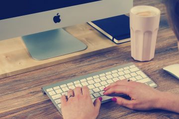 A woman types on an Apple keyboard