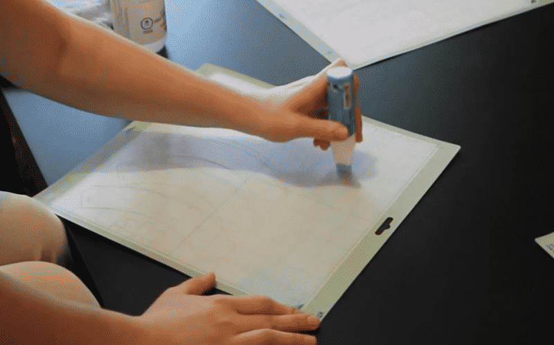 A woman applies Zig 2-way Glue to her Cricut mat to make it sticky again