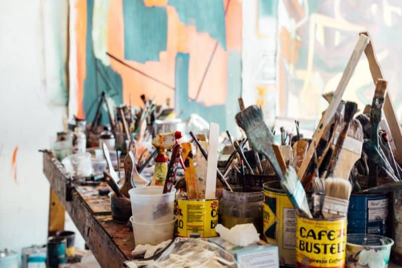 A messy craft room with paint brushes soaking