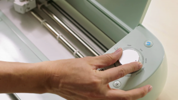 A woman sets the cut settings on a Cricut using the Smart Set Dial.
