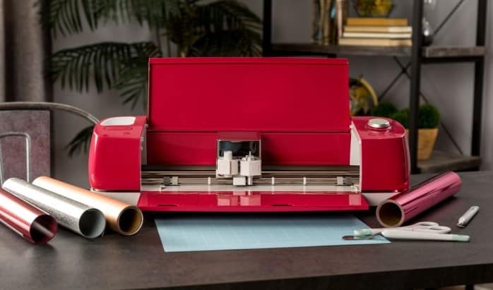 A bright red Explore Air 2 sits open on a desk with vinyl and cutting mat.