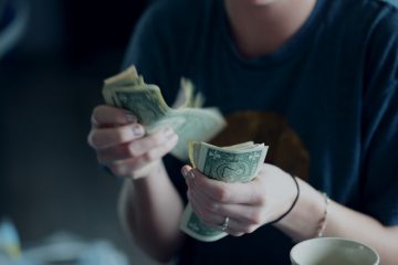 A woman pulls dollar bills out of her pocket.