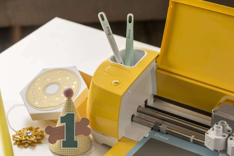 A bright yellow Cricut Explore Air 2 holds tools in the convenient accessory storage.